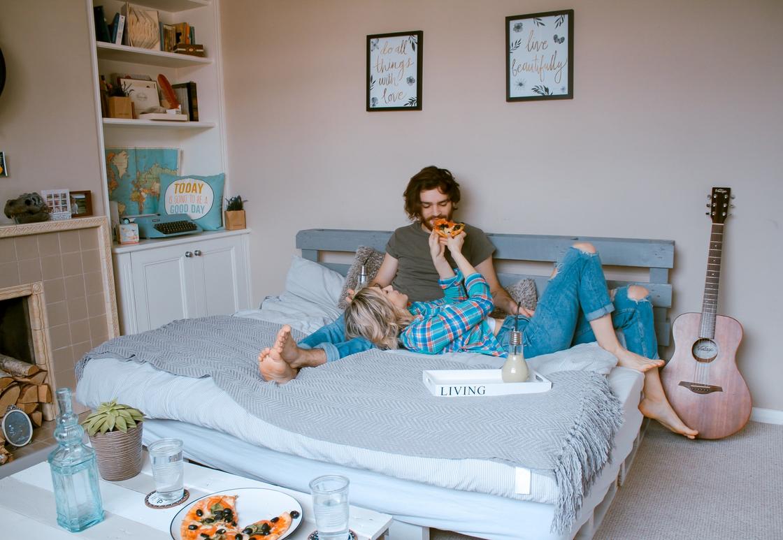 Девушка лежит на коленях у мужчины, сидящего в кровати